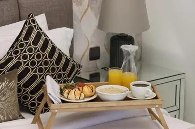 a tray of breakfast food on a bed with orange juice at Livbnb - 3BR Plus 1 with Burj and Fountain Views in Dubai