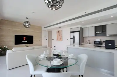 a kitchen and living room with a glass table and chairs at Livbnb-Beachfront 3BR with Marina Harbour Panorama in Dubai