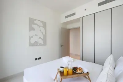 a white bedroom with a table with a tray of food at Livbnb-Beachfront 3BR with Marina Harbour Panorama in Dubai