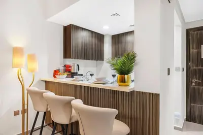 a kitchen with a bar with white chairs and a counter at Luxury 1BR in Business Bay - Close to Dubai Mall, Burj Khalifa & City Sights in Dubai