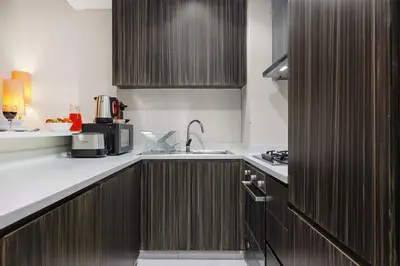 a kitchen with wooden cabinets and a sink in it at Luxury 1BR in Business Bay - Close to Dubai Mall, Burj Khalifa & City Sights in Dubai