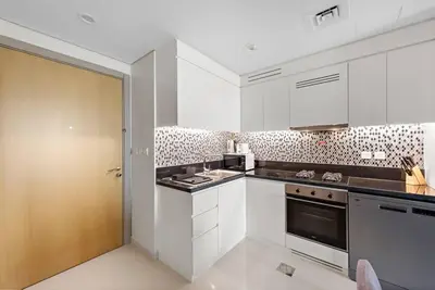 a kitchen with white cabinets and a brown door at Modern 2-Bedroom Apartment in Aykon Tower C in Dubai