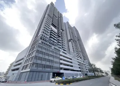 a tall white building with cars parked in front of it at Stylish Studio with Pool, Gym & Tasteful Decor in Dubai