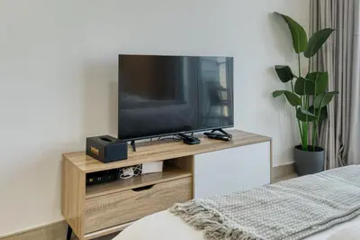 a television on a wooden stand in a bedroom at Stylish Studio with Pool, Gym & Tasteful Decor in Dubai