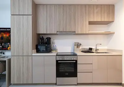 a kitchen with white cabinets and a stove top oven at Brand new Studio in Business Bay, Missoni Tower in Dubai