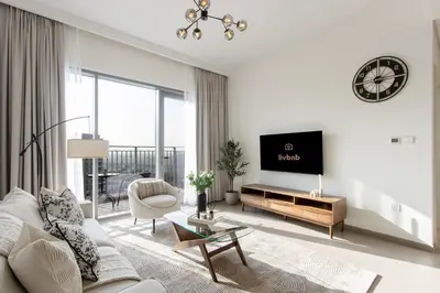 a living room with a couch and a tv at Livbnb - Stylish 1B in Park Heights Dubai Hills in Dubai