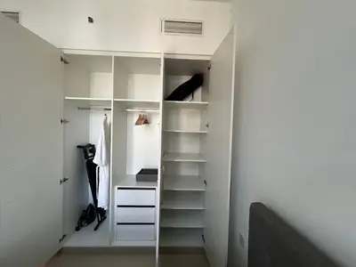 a white walk in closet with white shelves at Shared Apartment In Dubai Hills in Dubai