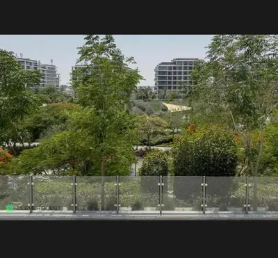 a tree behind a fence with buildings in the background at Shared Apartment In Dubai Hills in Dubai