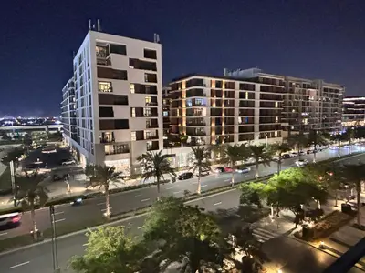 a city street with two tall buildings at night at Shared Apartment In Dubai Hills in Dubai