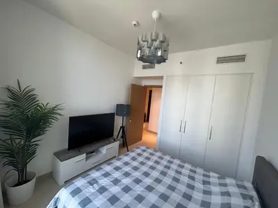 a bedroom with a bed and a flat screen tv at Shared Apartment In Dubai Hills in Dubai