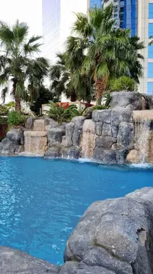 a swimming pool with a waterfall and palm trees at 1BR Tower B Paramount Apartment in Dubai
