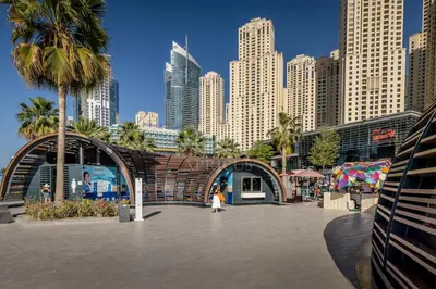 a woman walking in front of a city with tall buildings at Bright apartment in JBR few steps from the beach in Dubai