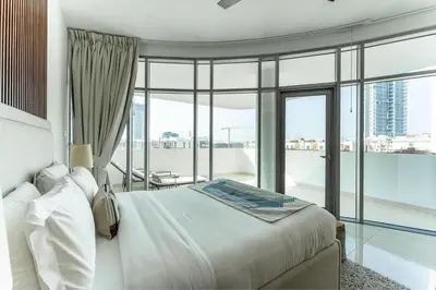 a bedroom with a white bed and a large window at HAVN - 1 Bedroom Apartment in Villa Pera, JVC in Dubai