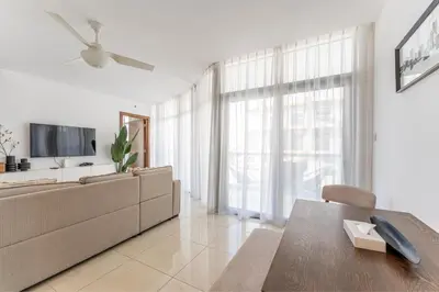 a living room with a couch and a tv at HAVN - 1 Bedroom Apartment in Villa Pera, JVC in Dubai