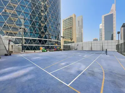 a tennis court in front of a building at Chic 1BR APT with Pool, Gym, BBQ, Tennis Court in Dubai