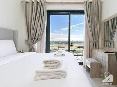a bedroom with a white bed with a view of the ocean at Balcony Studio Haven in Riviera in Dubai