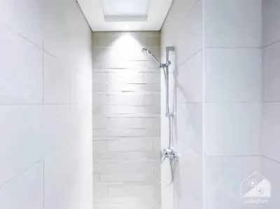 a bathroom with a shower with white tiles at Balcony Studio Haven in Riviera in Dubai