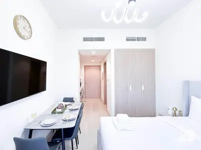 a white room with a bed and a table with chairs at Balcony Studio Haven in Riviera in Dubai