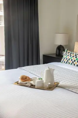 a tray with cups and saucers on a bed at Frank Porter - G24 Tower in Dubai