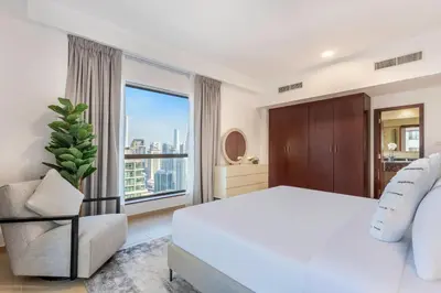 a bedroom with a white bed and a chair and a window at 2 Bedroom Apartment at Bahar 1 JBR by TSHH in Dubai