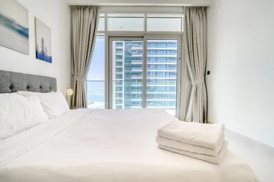 a bedroom with a large white bed with a large window at New 2 bedroom full sea view in Dubai