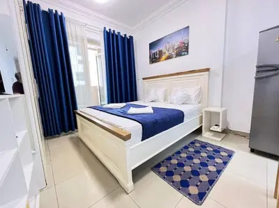 a bedroom with a bed with blue sheets and blue curtains at Brand New and Stylish Interior in Dubai