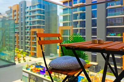 a wooden chair sitting on a balcony with a view of a city at Urban Oasis - Cosy Studio Retreat in Dubai