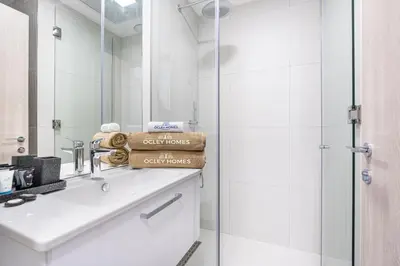 a white bathroom with a sink and a shower at Cozy & Bright Home in the Heart of JVC in Dubai