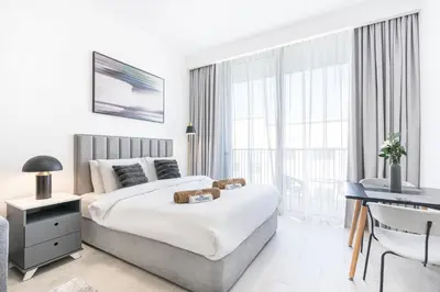 a hotel room with a large bed and a desk at Cozy & Bright Home in the Heart of JVC in Dubai