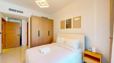 a bedroom with a white bed and a wooden door at Locations I Avanos Residence I Premium Modern 1BR I Cosy & Comfortable I Near Parks, Shops & Cafés in JVC in Dubai