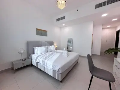 a white bedroom with a bed and a chair at Luxurious 2BR in Vezul Residence, Business Bay - 13AB01 in Dubai