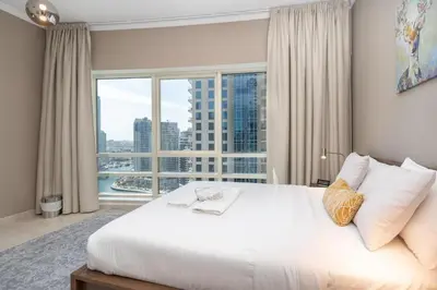 a bedroom with a large white bed with a large window at 2 Bedroom Apartment full Marina View in Dubai