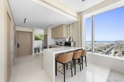 a kitchen with a bar with chairs and a view at Stunning 1-BR Apartment In Heart Of The Palm in Dubai