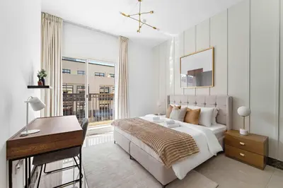 a bedroom with a bed and a desk and a window at Silkhaus Modern 2BDR in Pantheon Boulevard at JVC in Dubai