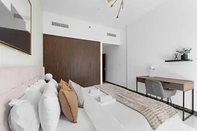 a bedroom with a large white bed and a desk at Silkhaus Modern 2BDR in Pantheon Boulevard at JVC in Dubai