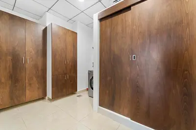 a bathroom with wooden cabinets and a toilet at Silkhaus Modern 2BDR in Pantheon Boulevard at JVC in Dubai