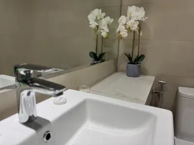 a bathroom with a sink and a mirror and flowers at ASHRI luxurious apt in Meydan Riviera 44 in Dubai