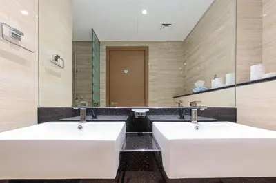 two white sinks in a bathroom with a mirror at 1BR Apt Residence Along Business Bay Canal in Dubai