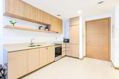 a kitchen with wooden cabinets and a door at 1BR Apt Residence Along Business Bay Canal in Dubai