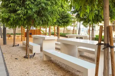 a row of white benches in a park with trees at Glow Sky Suite Trendy 1BR- Dubai Mall Access by Maxx Value Homes in Dubai