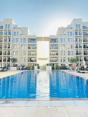 a swimming pool in front of some apartment buildings at Lovely calm 3BR Apt Easy Accessibility to central Dubai with huge balcony and pool view Town Square in Dubai