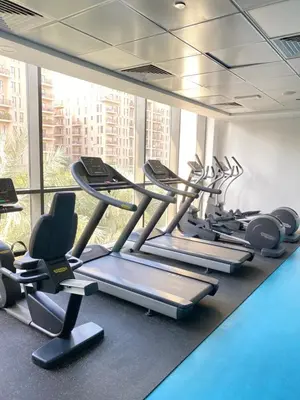 a gym with a row of treadmills and chairs at Lovely calm 3BR Apt Easy Accessibility to central Dubai with huge balcony and pool view Town Square in Dubai
