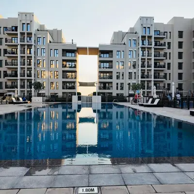 an empty swimming pool in front of apartment buildings at Lovely calm 3BR Apt Easy Accessibility to central Dubai with huge balcony and pool view Town Square in Dubai