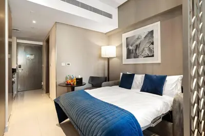 a bedroom with a large bed with a blue blanket at Luxury Smart Studio with Canal View Business Bay - Damac Maison Prive in Dubai