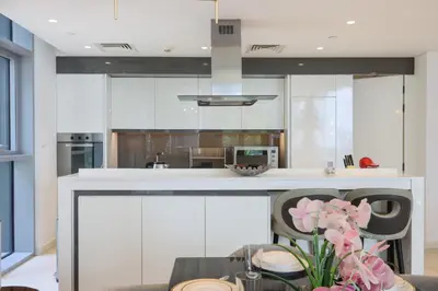 a kitchen with white cabinets and a table with flowers at Livbnb - Luxury 3B with Maid's Room, Partial Sea View in Dubai