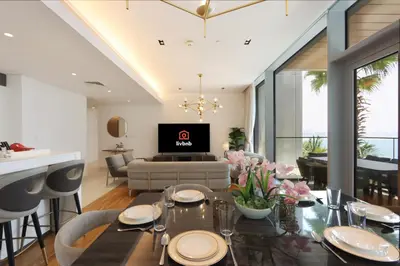 a living room with a dining table and a tv at Livbnb - Luxury 3B with Maid's Room, Partial Sea View in Dubai