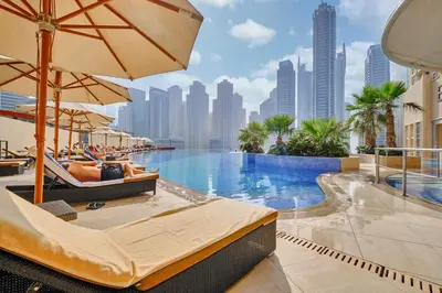 a hotel pool with chairs and umbrellas and a city at StayShort - Grand Stay in this 1 Bedroom Flat that Sleeps 4 in Dubai