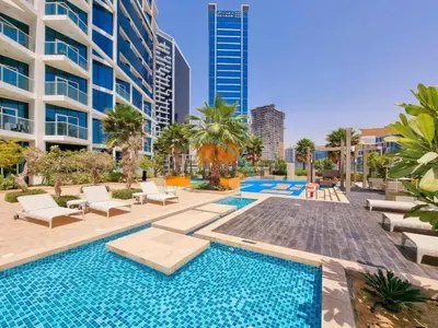 a swimming pool with chairs and a building at Luxury Studio Apartment in Prive By Damac B, Business Bay by Deluxe Holiday Homes in Dubai