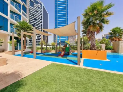 a pool with a playground with palm trees and buildings at Luxury Studio Apartment in Prive By Damac B, Business Bay by Deluxe Holiday Homes in Dubai