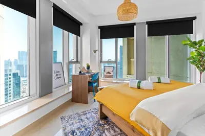 a bedroom with a bed and a desk and windows at Stylish 1BR with Iconic Burj and Fountain Views, Free Luxury Airport Pick Up Service in Dubai